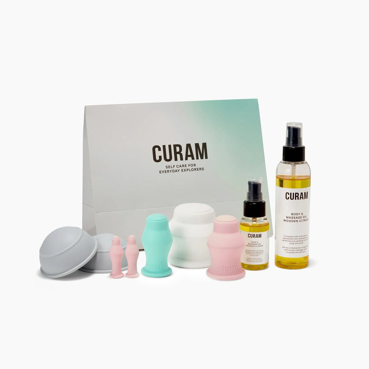 Curam Complete Kit med varumärkt presentpåse, med silikonkoppar i grå, mintgrön, vit och rosa för kropp och ansikte, tillsammans med två flaskor massageolja för ett komplett koppningsset för hemmabruk.