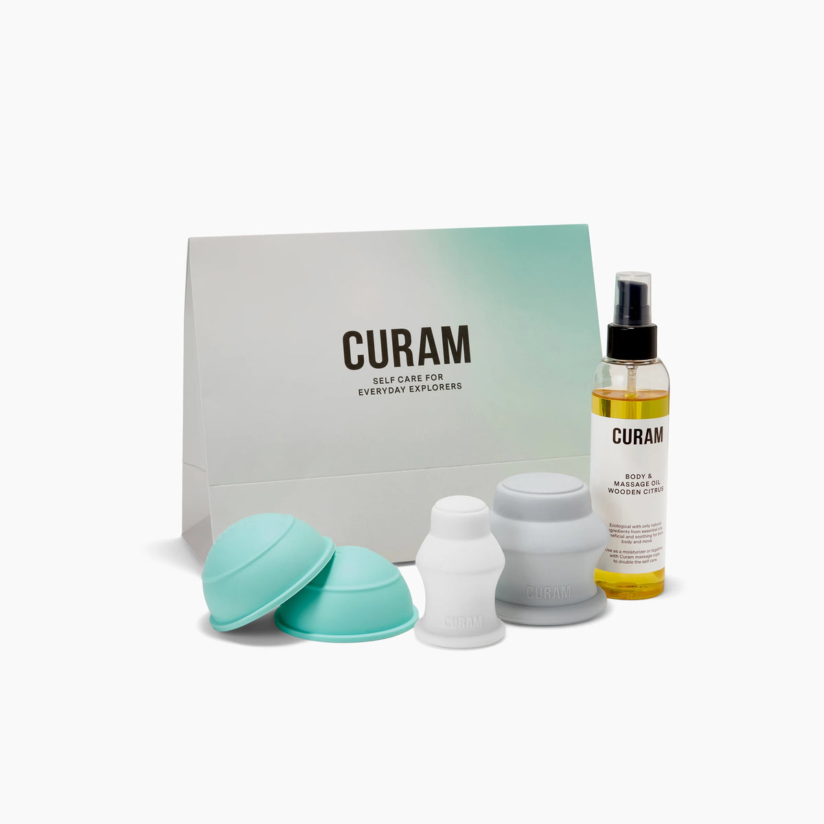 Curam Body Kit Small with three silicone massage cups in turquoise and white, Wooden Citrus Body and Massage Oil, and minimalist branded packaging displayed on a clean white surface.