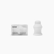 Curam Dynamic Mini Cup i vit silikon bredvid sin minimalistiska förpackning mot en ren vit bakgrund.